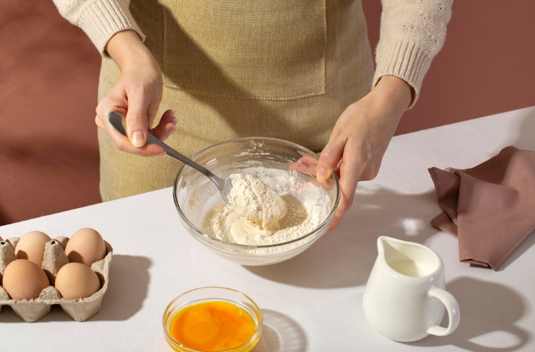 close up hands holding spoon and bowl for cake making